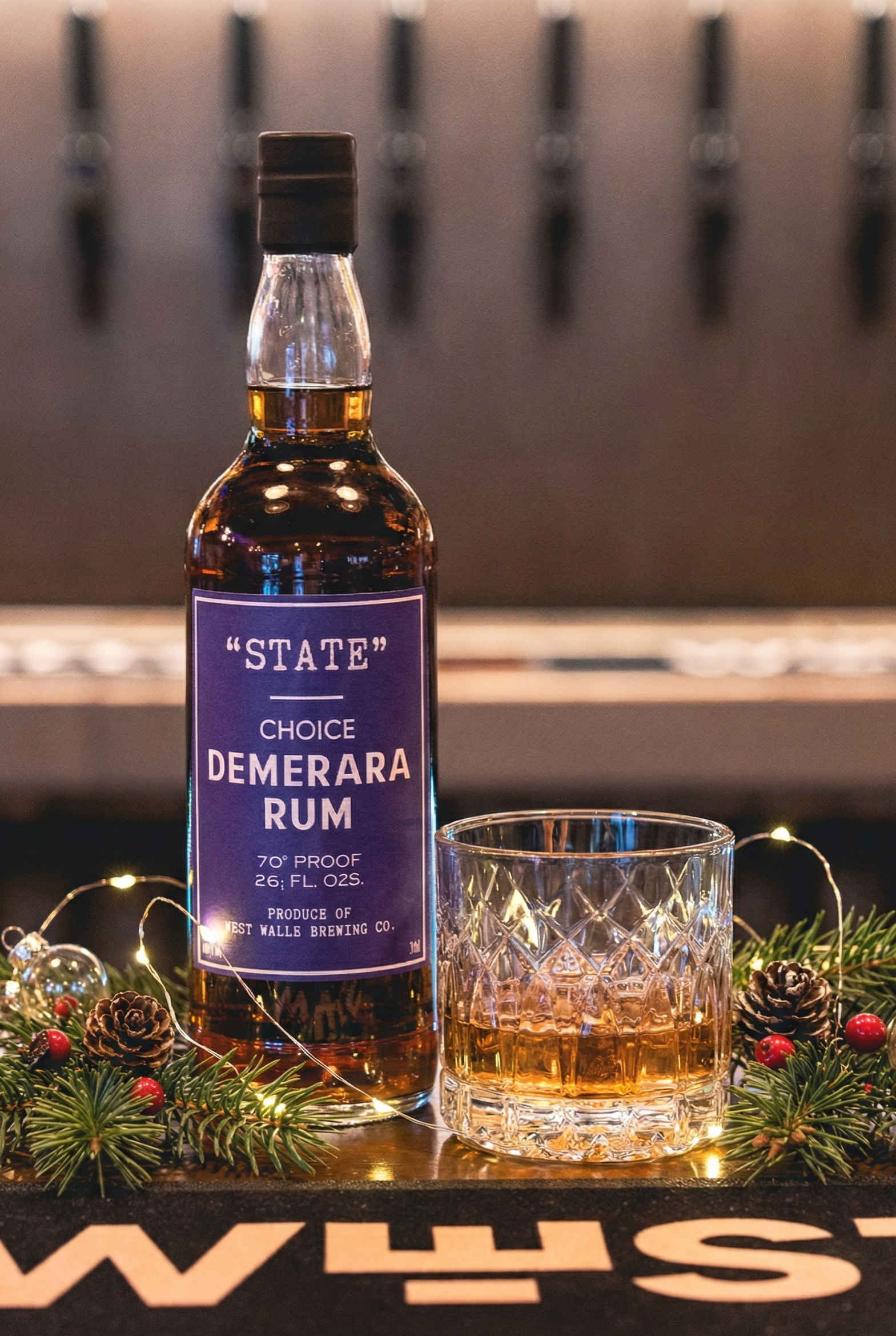 Bottle of 'State' Choice Demerara Rum with a glass on a bar counter.